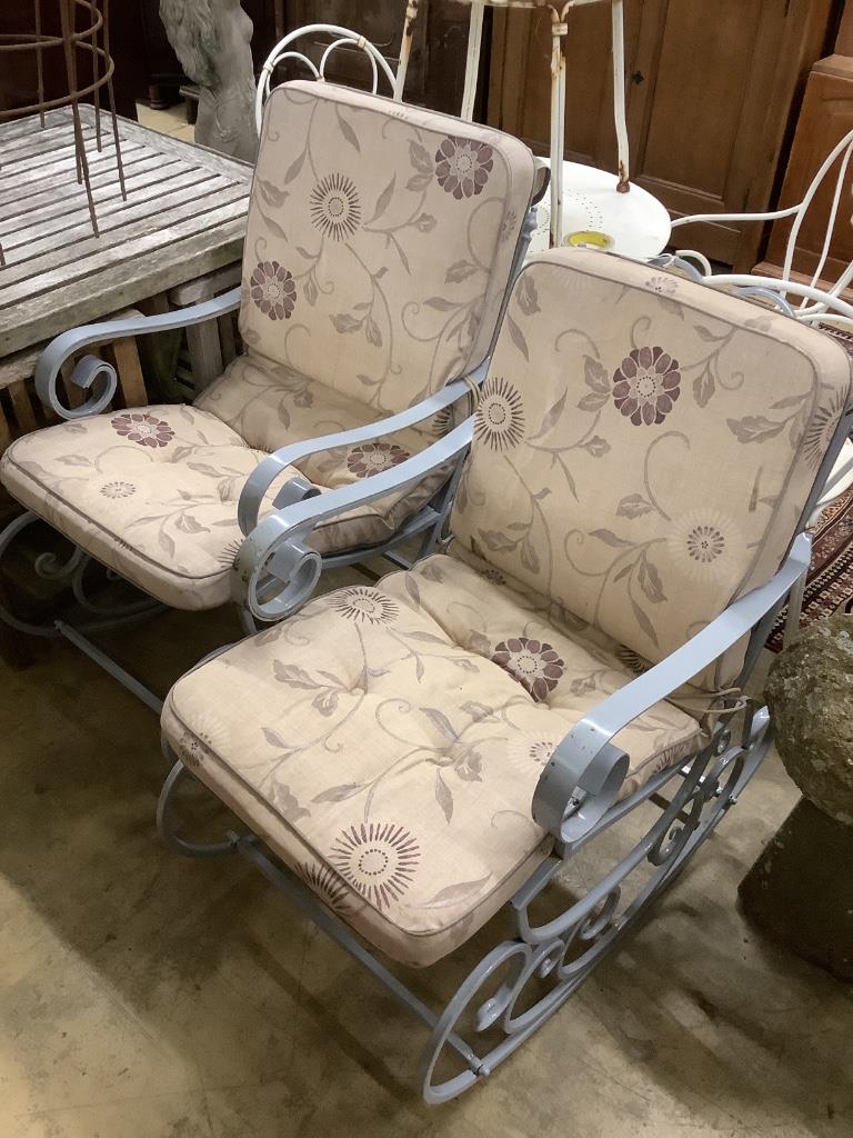 A pair of painted wrought iron garden rocking armchairs with cushion seats, width 57cm, depth 86cm, height 93cm